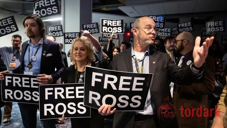 A crowd of supporters holding black-and-white 'FREE ROSS' placards at a rally for Ross Ulbricht
